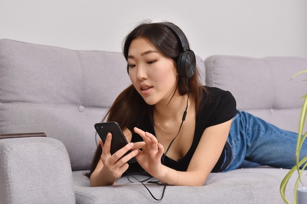 Mujer asiática en auriculares con smartphone