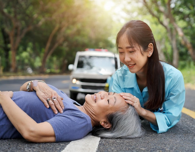 Foto mujer asiática ayudando a una persona mayor tendida en la carretera llama a una ambulancia de emergencia