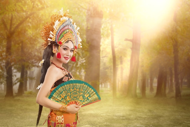 Foto mujer asiática bailando la danza tradicional balinesa (danza kembang girang) en el campo