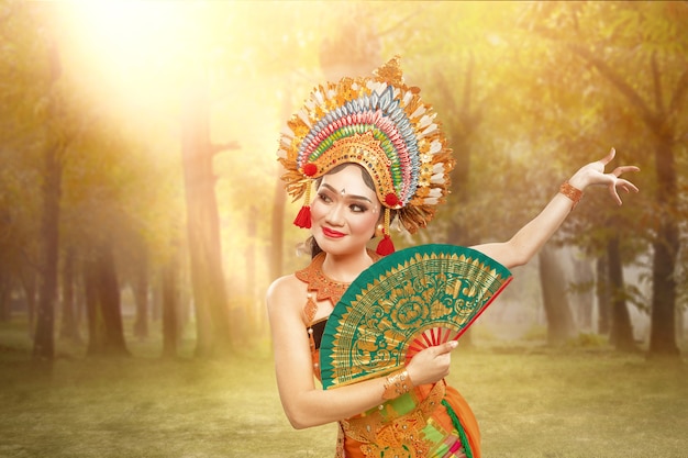 Foto mujer asiática bailando la danza tradicional balinesa (danza kembang girang) en el campo