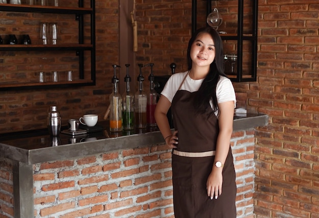 Mujer asiática barista smilling mirar cámara en cafe