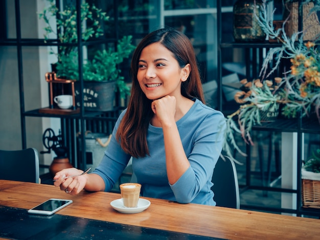 Mujer asiática bebiendo café en café cafetería