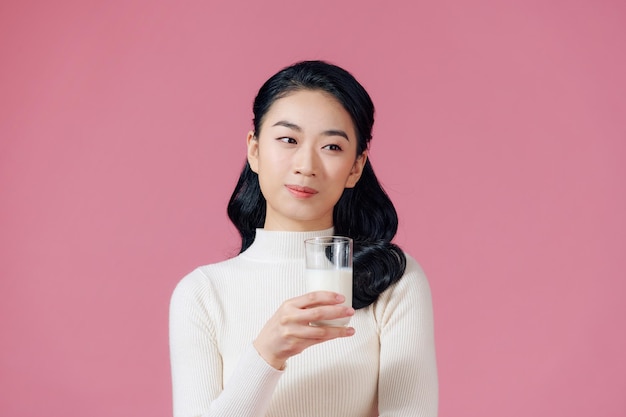 Mujer asiática bebiendo leche en rosa