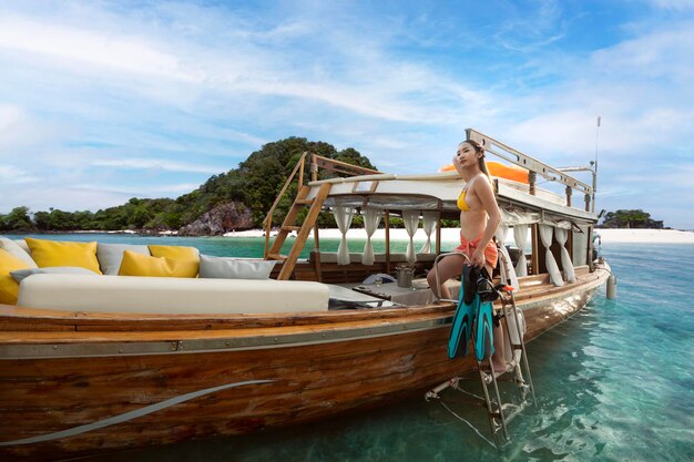 Mujer asiática en bikini haciendo snorkel en la isla Phi Phi con un barco boscoso cerca de la isla Phuket