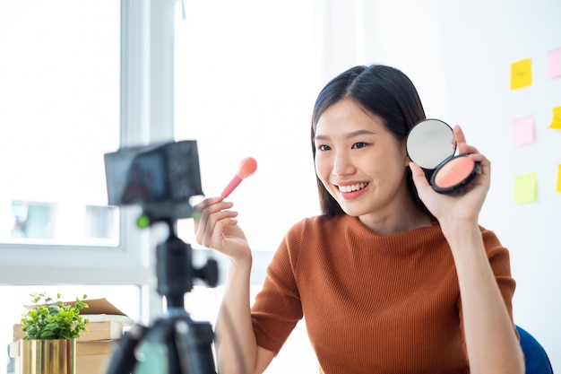 Mujer asiática blogger de belleza vlogger enseñando un tutorial cosmético de maquillaje a través de Internet en línea transmitiendo en vivo