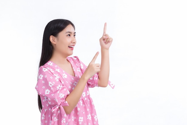 Mujer asiática con cabello largo negro en camisa rosa muestra presente algo sobre fondo blanco