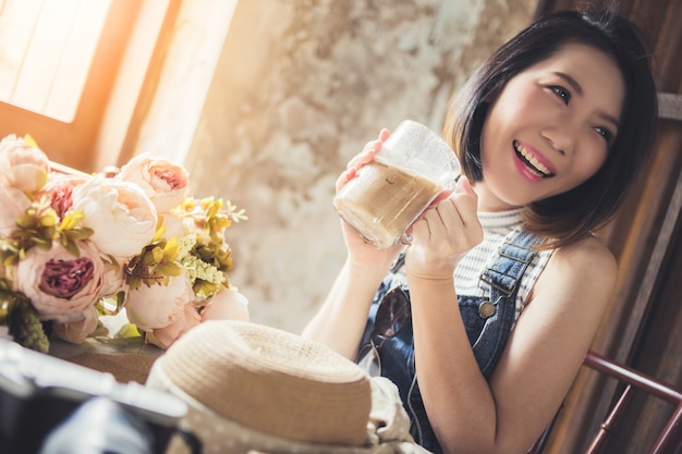 Mujer asiática con café cerca de una ventana