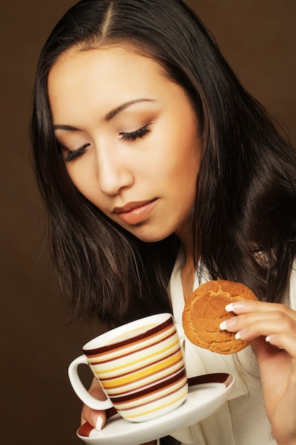 Mujer asiática con café y galletas.