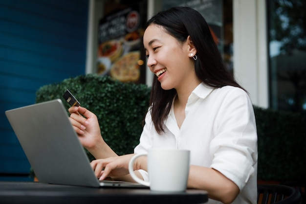 Foto mujer asiática en un café trabajando en una computadora portátil