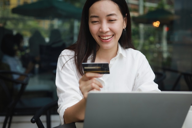 Mujer asiática en un café trabajando en una computadora portátil