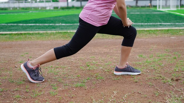 Mujer asiática calentando antes de correr. Cerrar piernas