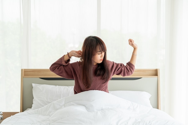 Mujer asiática en la cama y despertarse por la mañana