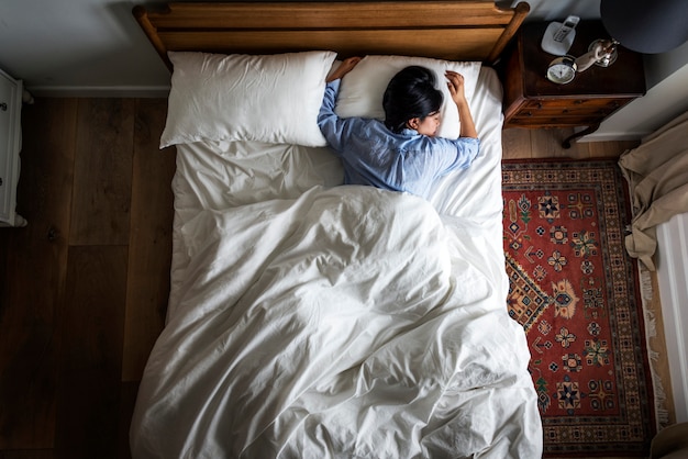 Mujer asiática en la cama durmiendo sola