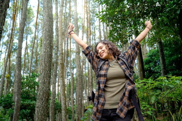 Mujer asiática caminando en el bosque con una expresión emocionada