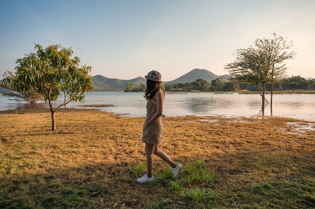 Mujer asiática caminando en el lado del embalse y vistas a la montaña en la noche