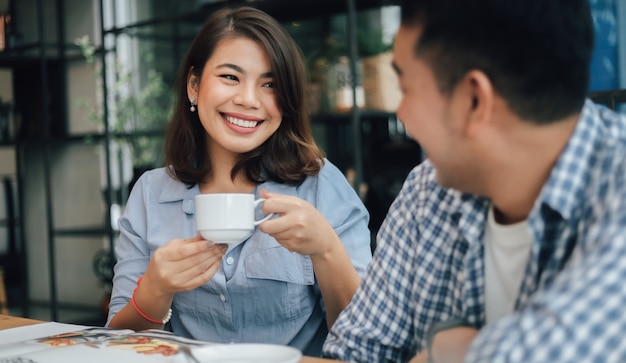 Foto mujer asiática en camisa azul en la cafetería tomando café y hablando con una sonrisa de novio y cara feliz