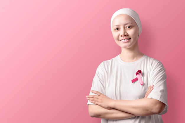 Mujer asiática en una camisa blanca con cinta rosa en rosa