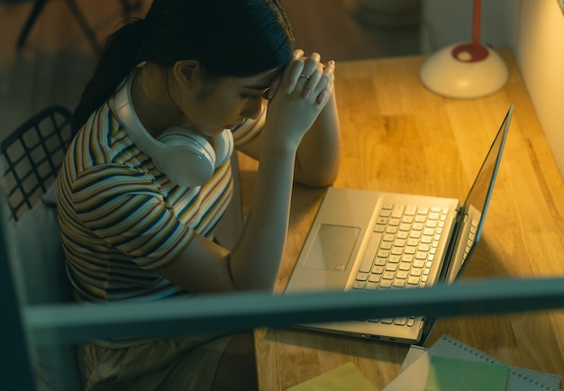 Mujer asiática cansada tratando de trabajar por la noche