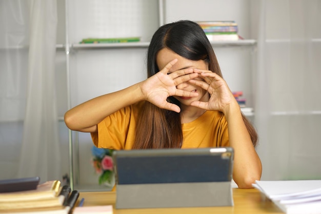 Mujer asiática en casa con dolor en el ojo por mirar una computadora durante mucho tiempo