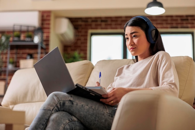 Mujer asiática en casa viendo una plataforma de suscripción de transmisión de películas en línea, series de películas de entretenimiento tecnología web de Internet que transmite una nueva aplicación digital de medios en una computadora portátil