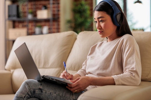 Mujer asiática en casa viendo una plataforma de suscripción de transmisión de películas en línea, series de películas de entretenimiento tecnología web de Internet que transmite una nueva aplicación digital de medios en una computadora portátil