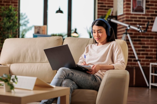 Mujer asiática en casa viendo una plataforma de suscripción de transmisión de películas en línea, series de películas de entretenimiento tecnología web de Internet que transmite una nueva aplicación digital de medios en una computadora portátil