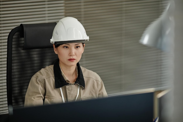 Mujer asiática con casco en el lugar de trabajo en la oficina y usando la computadora