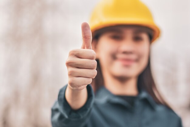 Mujer asiática con casco mostrando el pulgar hacia arriba