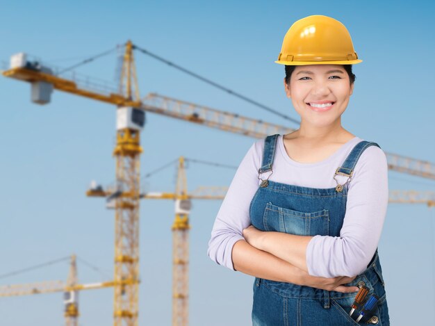 Mujer asiática con casco de seguridad amarillo con fondo de sitio de construcción