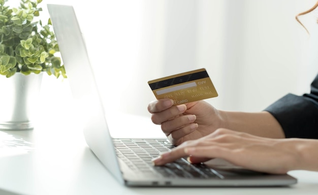 Mujer asiática chequeando los detalles del pedido en línea en la computadora y usando la información de la tarjeta de crédito ingresada en la computadora