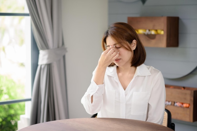 Una mujer asiática coloca sus manos cerca de su cabeza mientras sufre dolor de cabeza