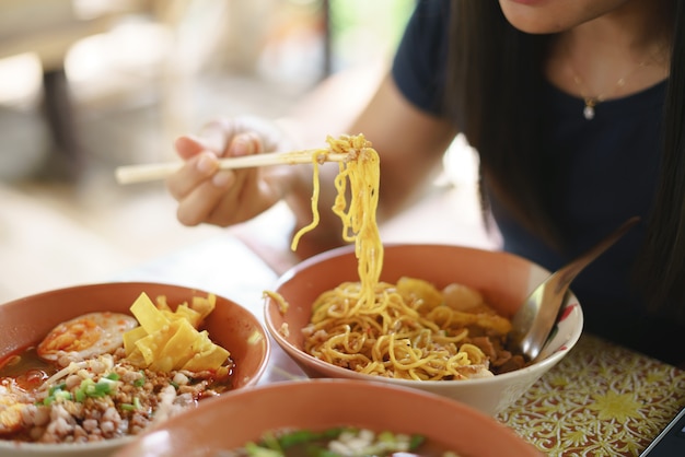 Mujer asiática comiendo fideos picantes y calientes