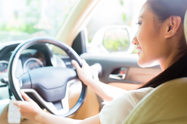 Mujer asiática, conducción, nuevo coche