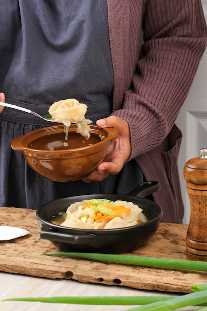 Mujer asiática Cook Mandu Jeongol o sopa Wonton, guiso de bola de masa tradicional coreano y chino con cebolleta picada