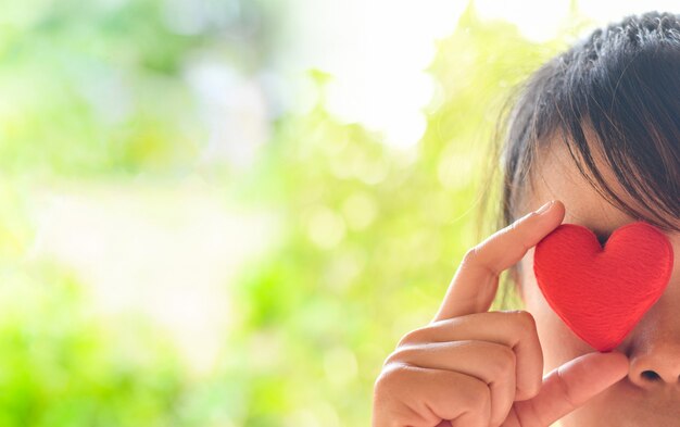 Mujer asiática con corazón rojo con los ojos cerrados