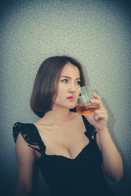 Mujer asiática corazón roto con whisky en la mano en estilo vintage. El corazón se rompe del concepto de mujer lovesad.