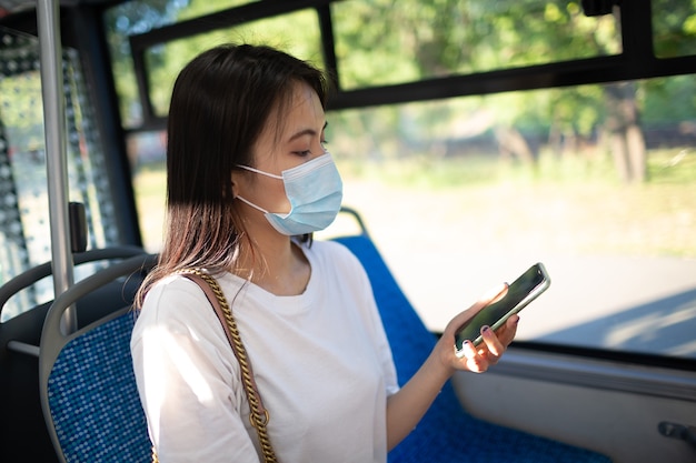 Mujer asiática dar un paseo en autobús de transporte público o tranvía con mascarilla