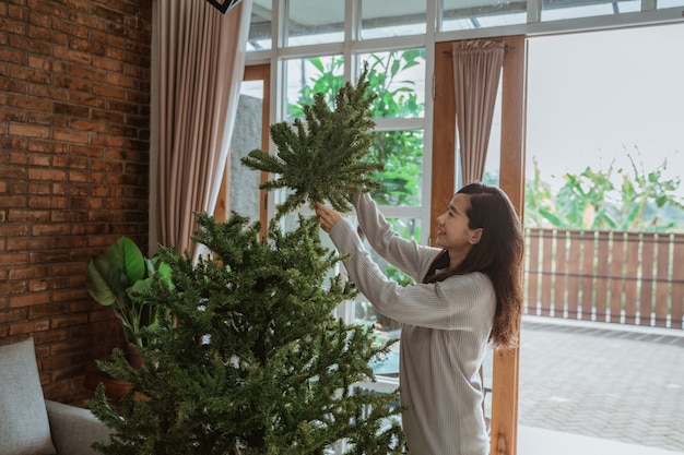 Mujer asiática decorando el árbol de Navidad