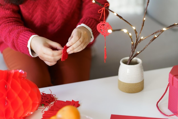 Mujer asiática decoró la casa para las celebraciones del Año Nuevo Chino poniendo un colgante tradicional al Año Nuevo Lunar Chino para la buena suerte La palabra china significa bendición