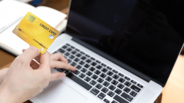 Mujer asiática descansando en el sofá y usando una computadora portátil para comprar en línea con tarjeta de crédito para registrarse
