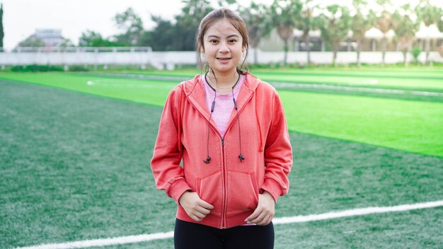 Mujer asiática después de correr usar chaqueta y auriculares