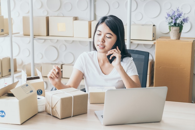 La mujer asiática disfruta mientras usa internet en la computadora portátil y el teléfono en la oficina