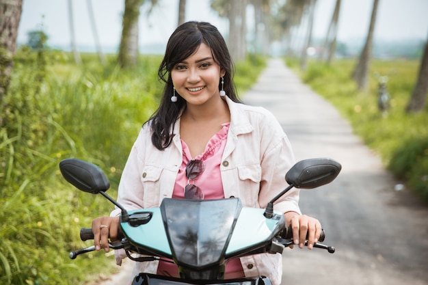 Mujer asiática disfruta montando su motocicleta en carretera tropical