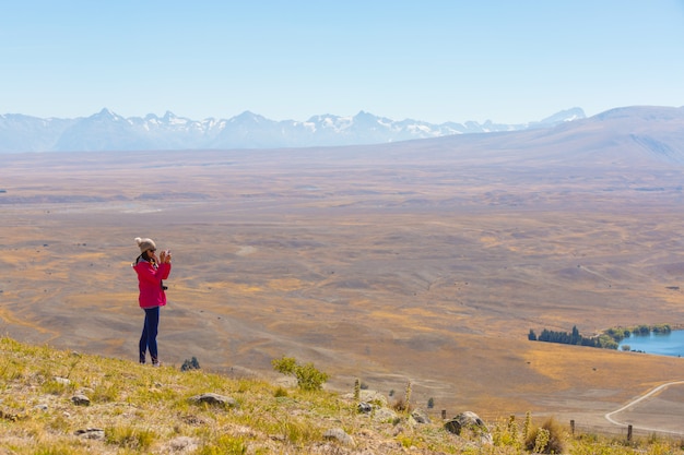 La mujer asiática disfruta de viaje en el lago Tekapo en Nueva Zelanda, concepto de los destinos del viaje