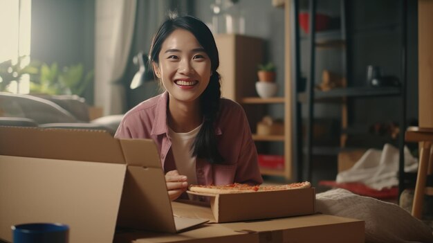 Mujer asiática disfrutando de pizza y viendo películas en streaming en medio de la mudanza a un nuevo apartamento Mujer Asiática alegre disfrutando