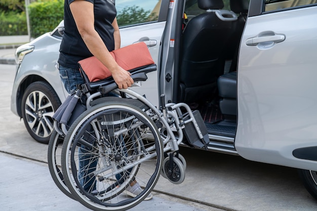 Mujer asiática doblando y levantando la silla de ruedas en su automóvil Concepto de accesibilidad