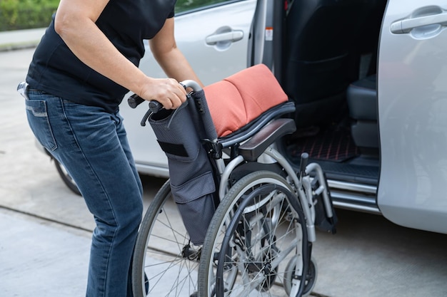 Mujer asiática doblando y levantando la silla de ruedas en su automóvil Concepto de accesibilidad