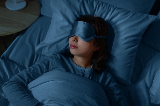 mujer asiática durmiendo en la cama en casa por la noche