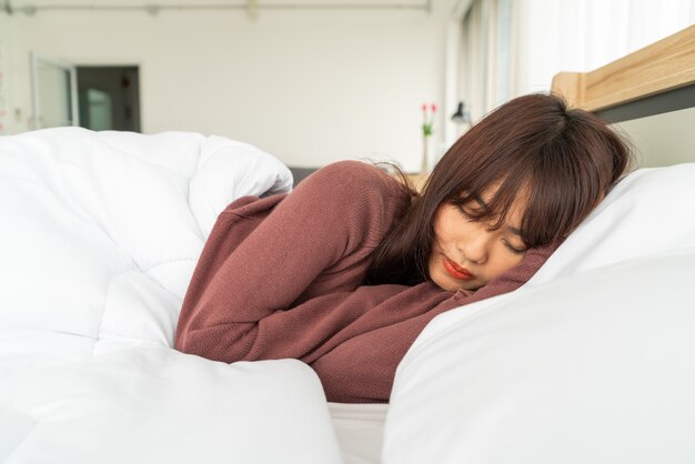 Mujer asiática durmiendo en la cama por la mañana