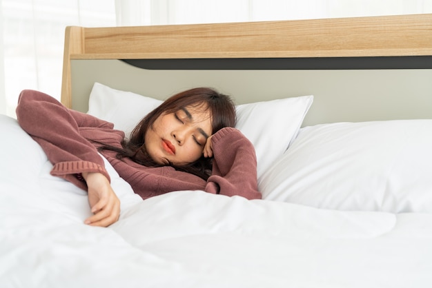 Mujer asiática durmiendo en la cama por la mañana